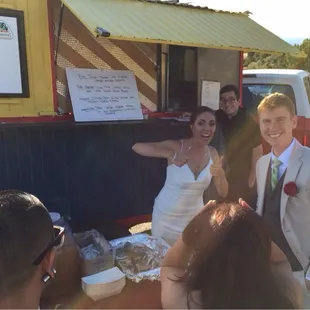 a bride and groom standing in front of a food truck