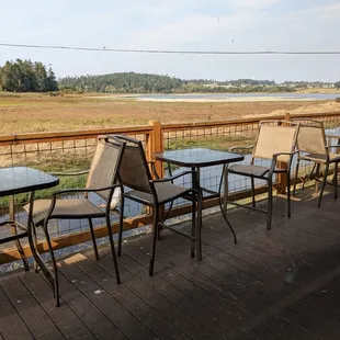 tables and chairs on a deck overlooking a marsh