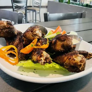 Jerk chicken wings with sauce on the side.