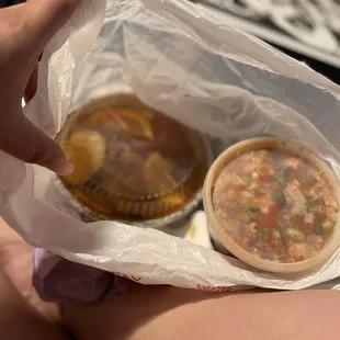 a person holding a plastic bag over a bowl of soup
