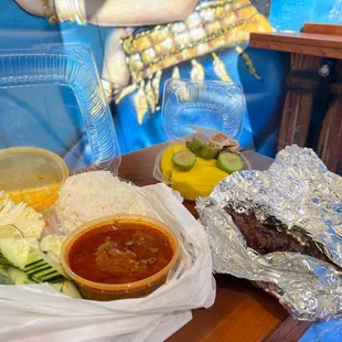 a tray of rice, meat, and vegetables