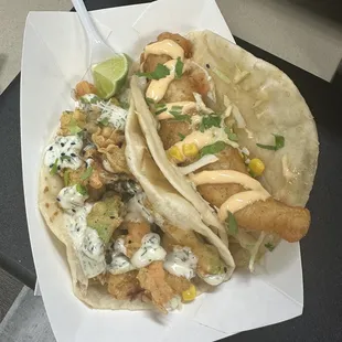 two fish tacos on a paper plate