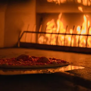 a pizza in front of a fireplace