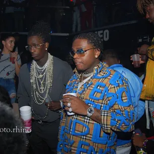 a man in a plaid shirt and sunglasses standing next to another man