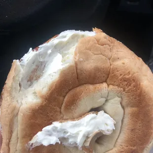 a person holding a bagel with cream on it