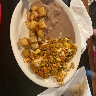 Choriquiles-chorizo, chilaquiles, eggs, and cheese. Refried beans and breakfast potatoes.