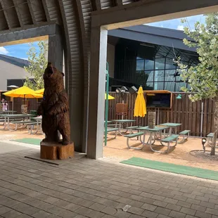 a large bear statue in front of tables and umbrellas