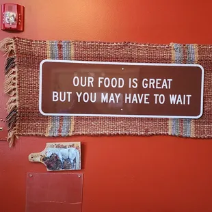 a sign that says our food is great but you may have to wait