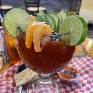 a cocktail with shrimp and lime garnish