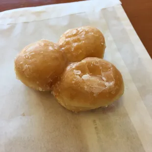 three glazed donuts on a napkin
