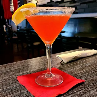 a cocktail in a martini glass with a slice of lemon on the rim