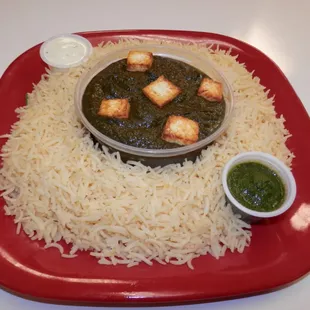 a red plate with rice and a bowl of sauce