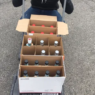 a woman sitting on a carton of bottles
