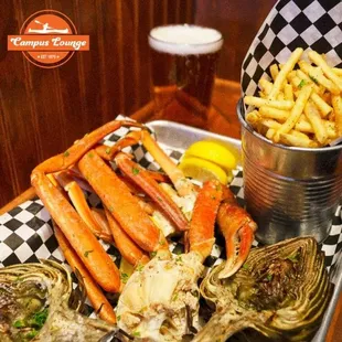 a seafood platter with crab legs and artichokes