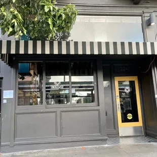 the front of a restaurant with black and white striped awning