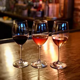 three glasses of wine on a bar