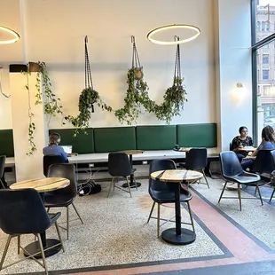 people sitting at tables with plants hanging from the ceiling