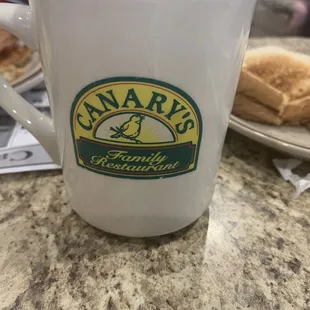 a white coffee mug with the name canary&apos;s on it
