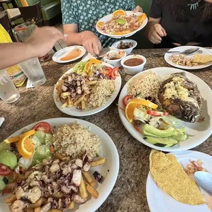 a group of people sitting at a table with plates of food