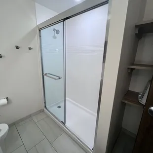 Large shower and shelves behind the door and a Landry basket
