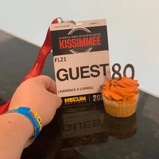 a person holding a ticket and a cupcake