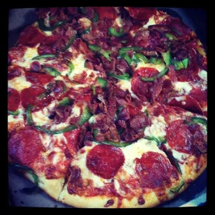 A large pizza with bacon, pepperoni, and bell peppers. Add your own toppings.
