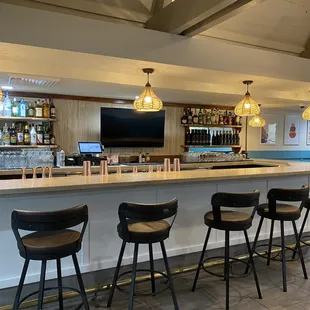 a bar with stools and a television