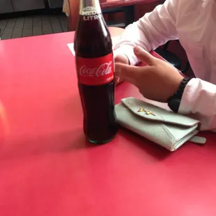 a man sitting at a table with a bottle of coke