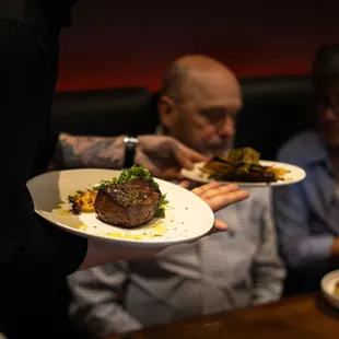 a waiter holding a plate of food