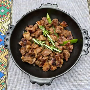 a skillet with meat and vegetables