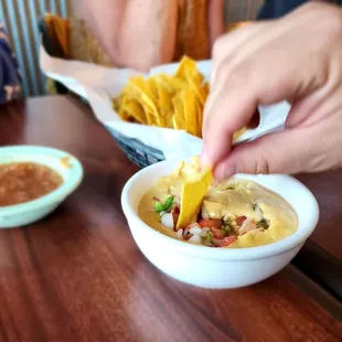 a person dipping a tortilla into a bowl
