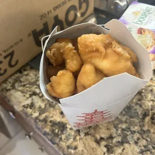 Chicken overflowing from container with either honey or sweet and sour on the side