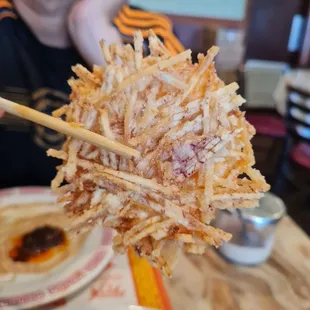 a close up of a fried item with chopsticks