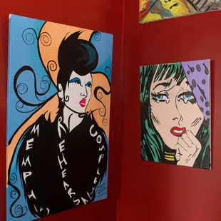 a red wall with paintings on it