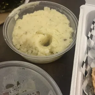 a bowl of mashed potatoes and a container of mashed potatoes