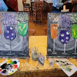 two paintings of wine glasses on a table