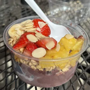 Açaí bowl with granola , strawberries, bananas, almonds , pineapple and honey.