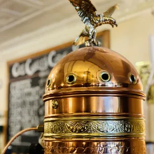 a copper coffee pot with a bird on top
