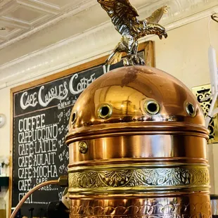 a copper coffee pot with a bird on top