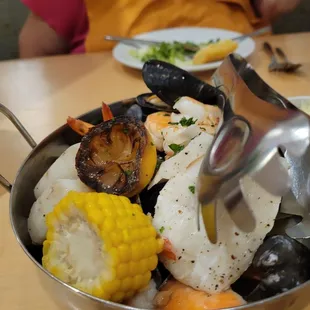 a bowl of seafood and corn on the cob