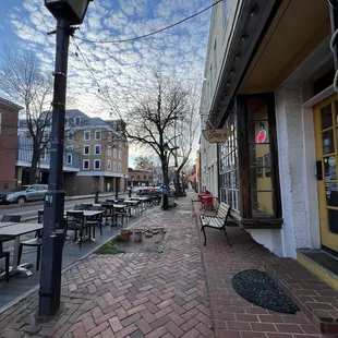 a brick sidewalk with tables and benches