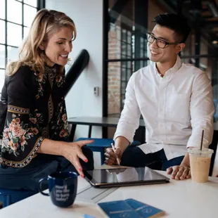 a man and a woman sitting at a table looking at a tablet