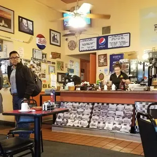Inside looking toward the display case for bakery and check out area where they are making fancy looking hot chocolate drinks.