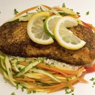 a fish fillet on a bed of rice and vegetables