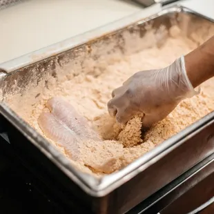 a hand in a pan of food