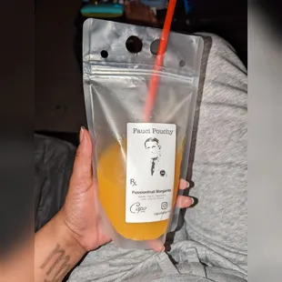 a person holding a bag of orange juice