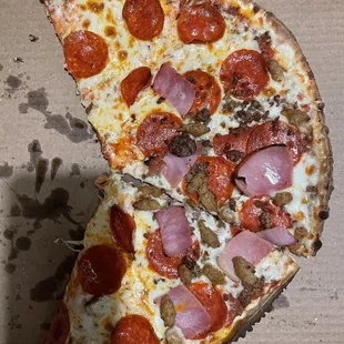 Half eaten 1/2 pepperoni 1/2 meat lovers thin crust pizza