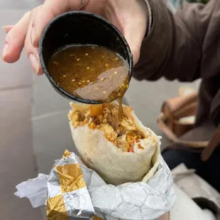 a person pouring a cup of coffee into a burrito