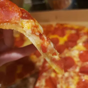 a hand holding a slice of pepperoni pizza