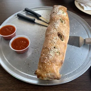 ows a pizza roll on a plate with sauces